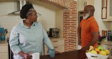 Afro-Amerikan son sınıf öğrencisi, evdeki mutfakta yaşlı bir kadına bir buket çiçek veriyor. Koronavirüs salgını sırasında karantina karantinasına sosyal uzaklık
