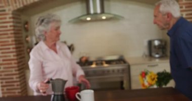 Mutfakta kıdemli beyaz bir çift var. Adam kadına yavaş çekimde çiçek veriyor. Coronavirus covid 19 tecridi sırasında evde vakit geçirmenin tadını çıkarıyor..