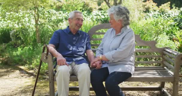 Feliz Pareja Ancianos Caucásicos Jardín Sonriendo Tomados Mano Sentados Banco — Vídeos de Stock