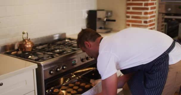 Biały Mężczyzna Fartuchu Wyjmuje Tacę Pieczonych Ciastek Piekarnika Kuchni Domu — Wideo stockowe