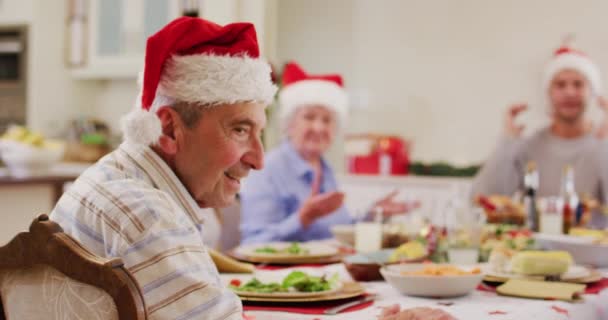 Noel Baba Şapkalı Beyaz Adamın Portresi Yemek Masasında Otururken Gülümsüyor — Stok video
