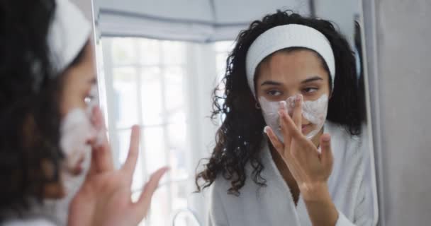 Gemischte Frau Die Badezimmer Gesichtscreme Aufträgt Bademantel Und Stirnband Zeitlupe — Stockvideo