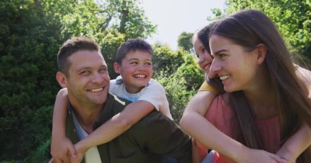 一对高加索夫妇背着儿子和女儿在花园里的画像 验尸官大流行期间的社会隔离措施 — 图库视频影像