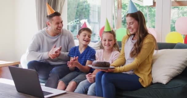 家族が拍手し 自宅で誕生日を祝う間 誕生日ケーキを保持パーティー帽子の白人女性 コロナウイルスの隔離中の社会的距離 — ストック動画