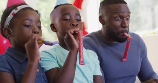 Famiglia Afroamericana Con Cappelli Festa Che Soffiano Soffiatori Mentre Siede — Video Stock