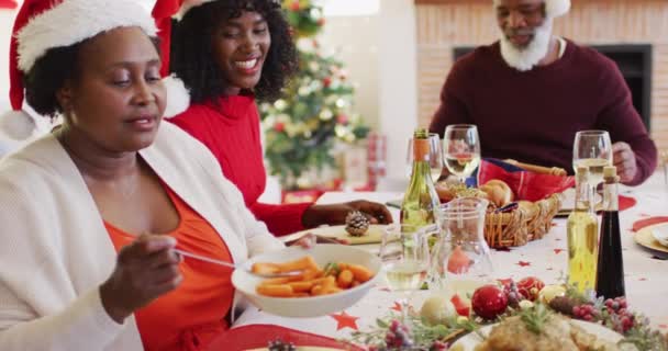 Eine Afroamerikanische Seniorin Mit Weihnachtsmannmütze Serviert Essen Teller Während Sie — Stockvideo