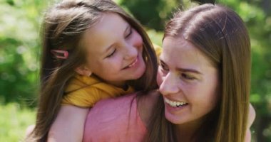 Bahçede sırtında kızını taşıyan beyaz bir annenin portresi. Koronavirüs salgını sırasında karantina karantinasına sosyal uzaklık