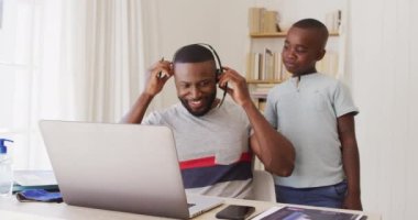 Afrikalı Amerikalı baba laptoptaki görüntülü sohbeti bitiriyor ve evde çalışırken oğluyla konuşuyor. Covid 19 koronavirüs karantina süresince sosyal mesafeler.