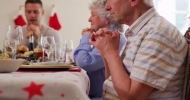 Beyaz bir aile yemek masasında oturup öğle yemeğinden önce birlikte dua ediyor. Evde noel. Noel kutlaması geleneği