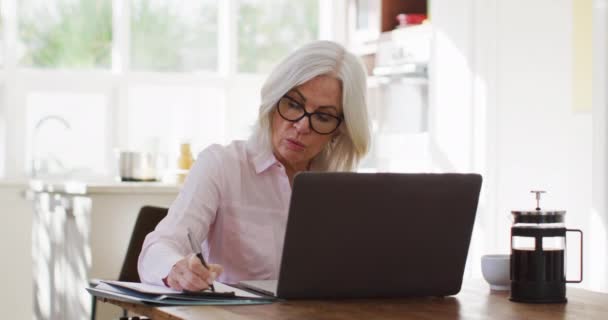 Senior Vrouw Met Een Bril Die Notities Maakt Laptop Gebruikt — Stockvideo