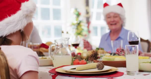 一个戴着圣塔帽的白人女孩的画像 圣诞节期间 我们一起坐在饭桌上吃午饭 圣诞节庆祝活动的传统概念 — 图库视频影像