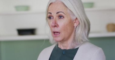 Yaşlı beyaz bir kadının portresi öksürüyor ya da koluna hapşırıyor, ağır çekimde. Coronavirus covid 19 salgını sırasında hijyen ve koruma.