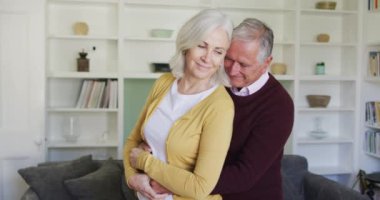 Mutlu Kafkasyalı çift kucaklaşıp, yavaşça dans ediyor ve gülümsüyor. Oturma odasında, ağır çekimde. Coronavirus covid 19 salgını sırasında evde birlikte vakit geçirmek..