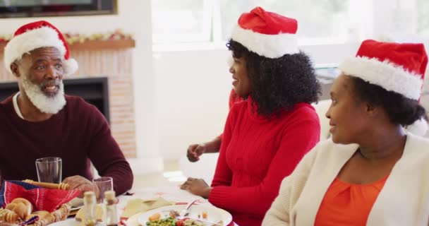 모자쓴 아프리카계 미국인 엄마를 껴안고 크리스마스 집에서 점심을 먹으며 식탁에 — 비디오