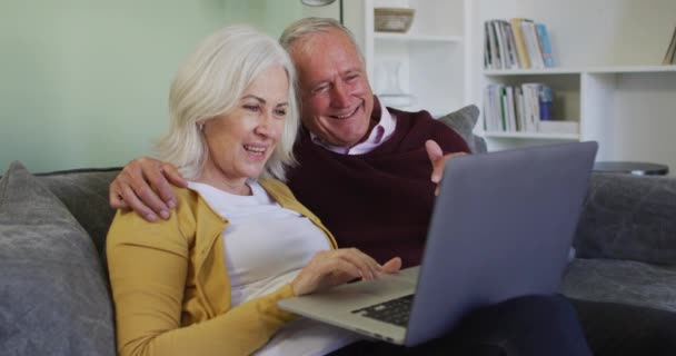 快乐的资深高加索夫妇用笔记本电脑打视频电话 坐在沙发上 慢吞吞地挥挥手微笑 食管癌大流行期间在家共度的美好时光 — 图库视频影像