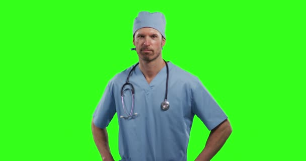 緑の画面の背景に白人男性医師 頭蓋骨を身に着けてカメラを見て腰を握っている男の肖像画 — ストック動画