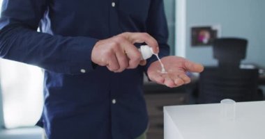 Modern ofiste el dezenfektanı kullanan bir adam. Coronavirus covid 19 salgını sırasında işyerinde hijyen ve sosyal mesafeler.