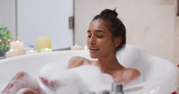 Смешанная расовая женщина лежит дома в ванной — стоковое видео