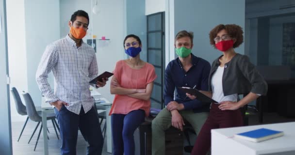 現代オフィスでフェイスマスクを身に着けている多様な同僚の肖像画 コロナウイルスの職場での衛生と社会的距離は19のパンデミックを克服しました — ストック動画