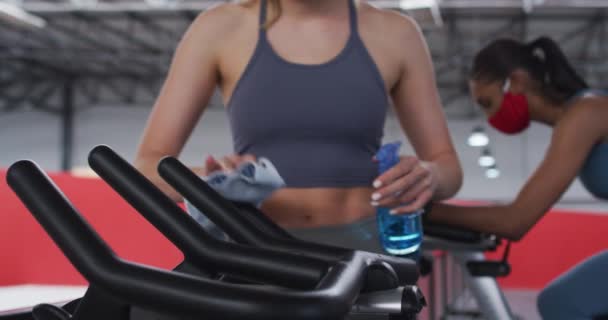 Caucasian Woman Disinfecting Exercise Bike Handlebars Gym Spraying Sanitizer Cleaning — Stock Video