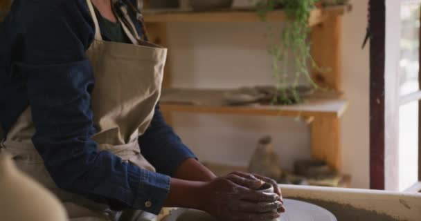 女陶工戴着面具和围裙 在陶瓷工作室的陶瓷轮上制作陶器 大肠病毒大流行期间陶器工作室的卫生与社会疏离D — 图库视频影像