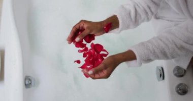 Karışık ırktan bir kadın küvetin yanında oturuyor.