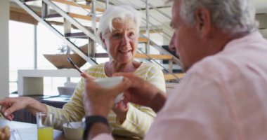 Üst düzey Kafkasyalı çift evde kahvaltı ederken birbirleriyle konuşuyorlar.