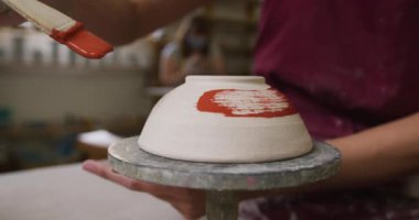 Çömlek atölyesinde çömlekçi çarkına önlük takan kadın çömlekçinin yakın görüntüsü. Coronavirus codemic 19 salgını sırasında çömlek atölyesinde hijyen ve sosyal mesafeler.