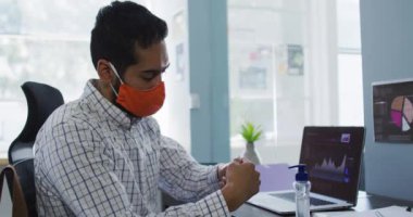 Orta Doğulu adam modern ofiste el dezenfektanı kullanıyor. Coronavirus covid 19 salgını sırasında işyerinde hijyen ve sosyal mesafeler.