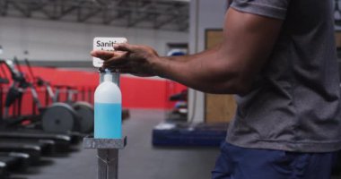 Afro-Amerikan bir adamın spor salonunda ellerini sterilize ettiği orta bölüm. Koronavirüs salgını sırasında karantinaya alınma