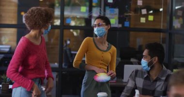 Modern ofiste dirseklerine dokunarak birbirini selamlayan yüz maskeleri takan çeşitli meslektaşlar. Coronavirus covid 19 salgını sırasında işyerinde hijyen ve sosyal mesafeler.