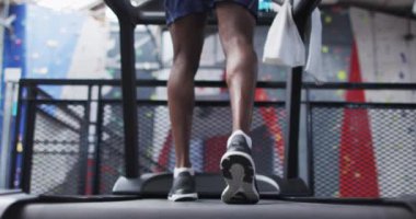 Spor salonunda koşu bandında koşan Afro-Amerikan bir adam. Koronavirüs salgını sırasında karantinaya alınma