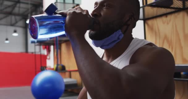 Hombre Afroamericano Usando Mascarilla Baja Bebiendo Gimnasio Tomando Descanso Entrenamiento — Vídeos de Stock