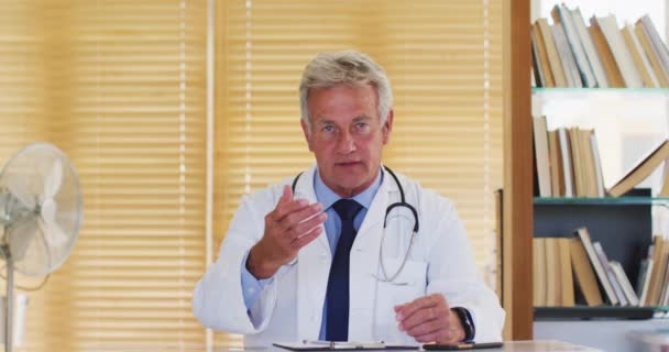 Portrét mužského bělocha lékaře mluvení při pohledu do kamery, zatímco sedí v nemocnici — Stock video