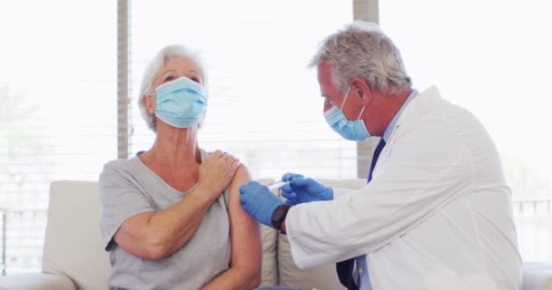หมอผิวขาวชายสวมหน้ากาก ให้ฉีดผู้หญิงผิวขาวอาวุโสที่โรงพยาบาล — วีดีโอสต็อก