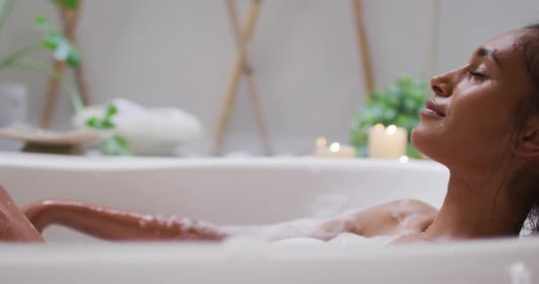 Mixed race woman lying in a bathtub at home — Stock Video