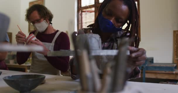 不同的男性和女性陶工都戴着面具和围裙在陶器工作室做陶器 大肠病毒大流行期间陶器工作室的卫生与社会疏离D — 图库视频影像