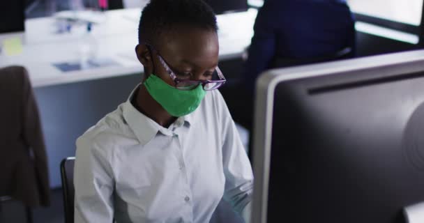 African American Woman Wearing Face Mask Using Computer While Sitting — Stock Video