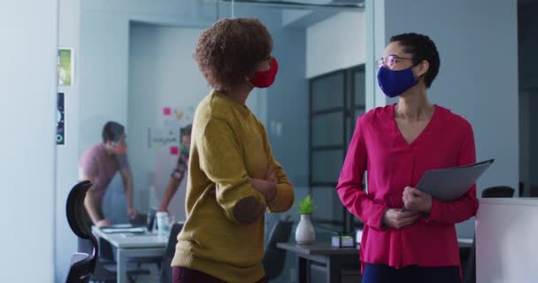 混血女同事在办公室戴口罩 眼镜蛇大流行期间工作场所的谈话和社交距离 — 图库视频影像