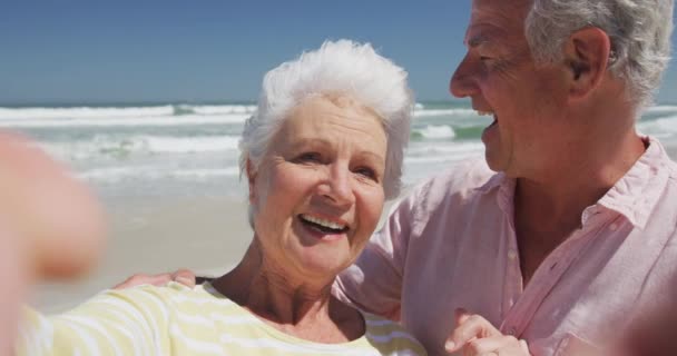 Porträt eines glücklichen älteren kaukasischen Paares, das am Strand Küsse in die Kamera pustet — Stockvideo