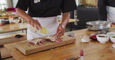 Çeşitli aşçılar yemek hazırlıyor ve gülümsüyor. Coronavirus covid 19 salgını sırasında profesyonel bir mutfakta sağlık ve hijyen..