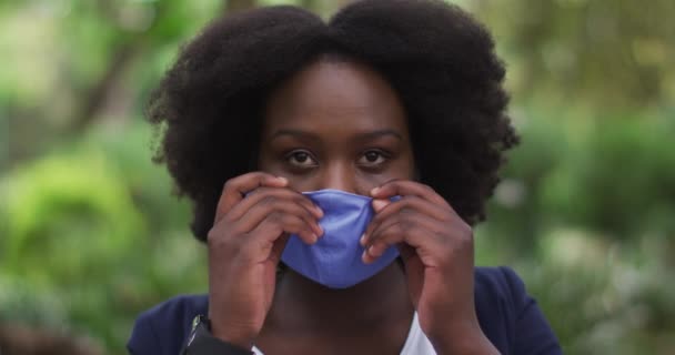 Afrikansk amerikansk kvinna klipper ansiktsmask på i parken — Stockvideo