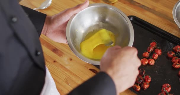 混合种族的男性厨师在碗里搅拌鸡蛋 科罗纳韦病毒大流行期间 在专业厨房里工作时的社会疏离 — 图库视频影像