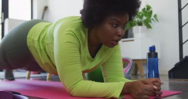 Afrika kökenli Amerikalı kadın vlogger egzersiz paspasına uzanmış çalışıyor.