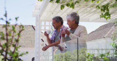 Bahçe balkonunda kahve içen son sınıf melez çift.