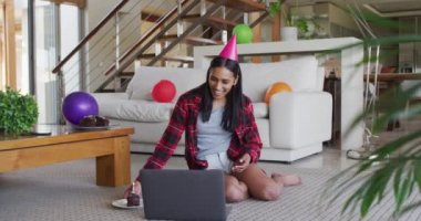 Karışık ırk kadını dizüstü bilgisayar kullanıyor ve elinde pasta tutarken görüntülü sohbet yapıyor.