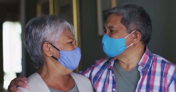 Senioren-Mixed-Race-Paar mit Gesichtsmasken steht umarmend im Flur — Stockvideo