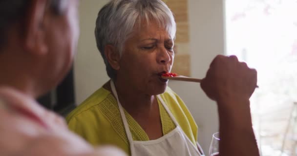 Starsza mieszana para przygotowująca jedzenie kobieta cieszy się smakiem z łyżki — Wideo stockowe