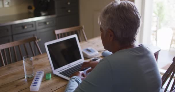 Senior mieszane rasy kobieta po konsultacji lekarskiej online za pomocą laptopa — Wideo stockowe