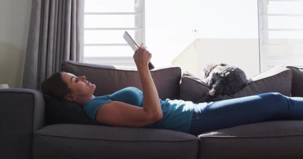 Blanke Vrouw Liggend Bank Met Hond Met Behulp Van Digitale — Stockvideo